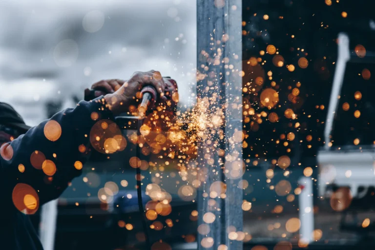 Close-up of a worker using a grinder, producing bright orange sparks.