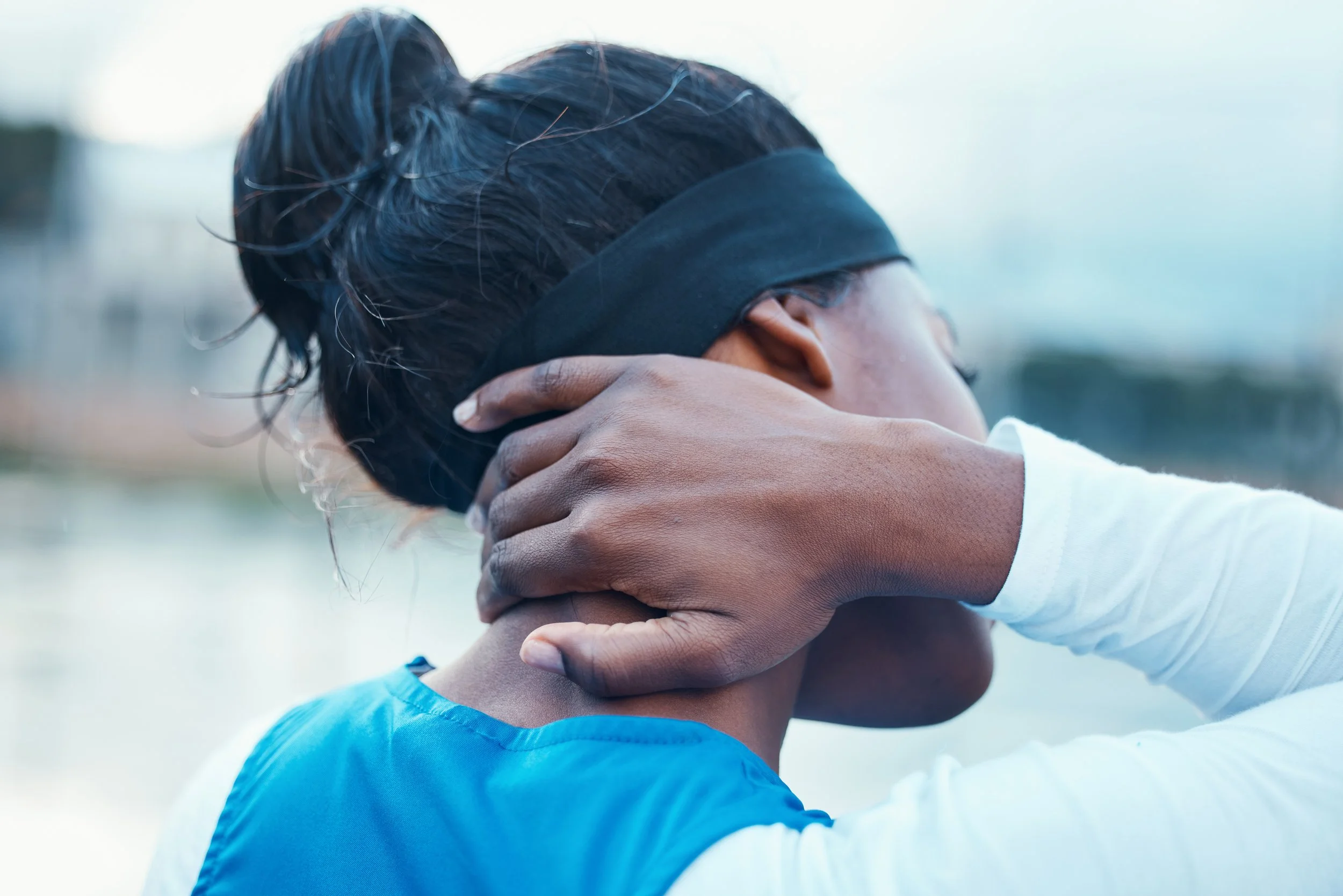 Rear view of a woman in sportswear holding her neck, outdoors.