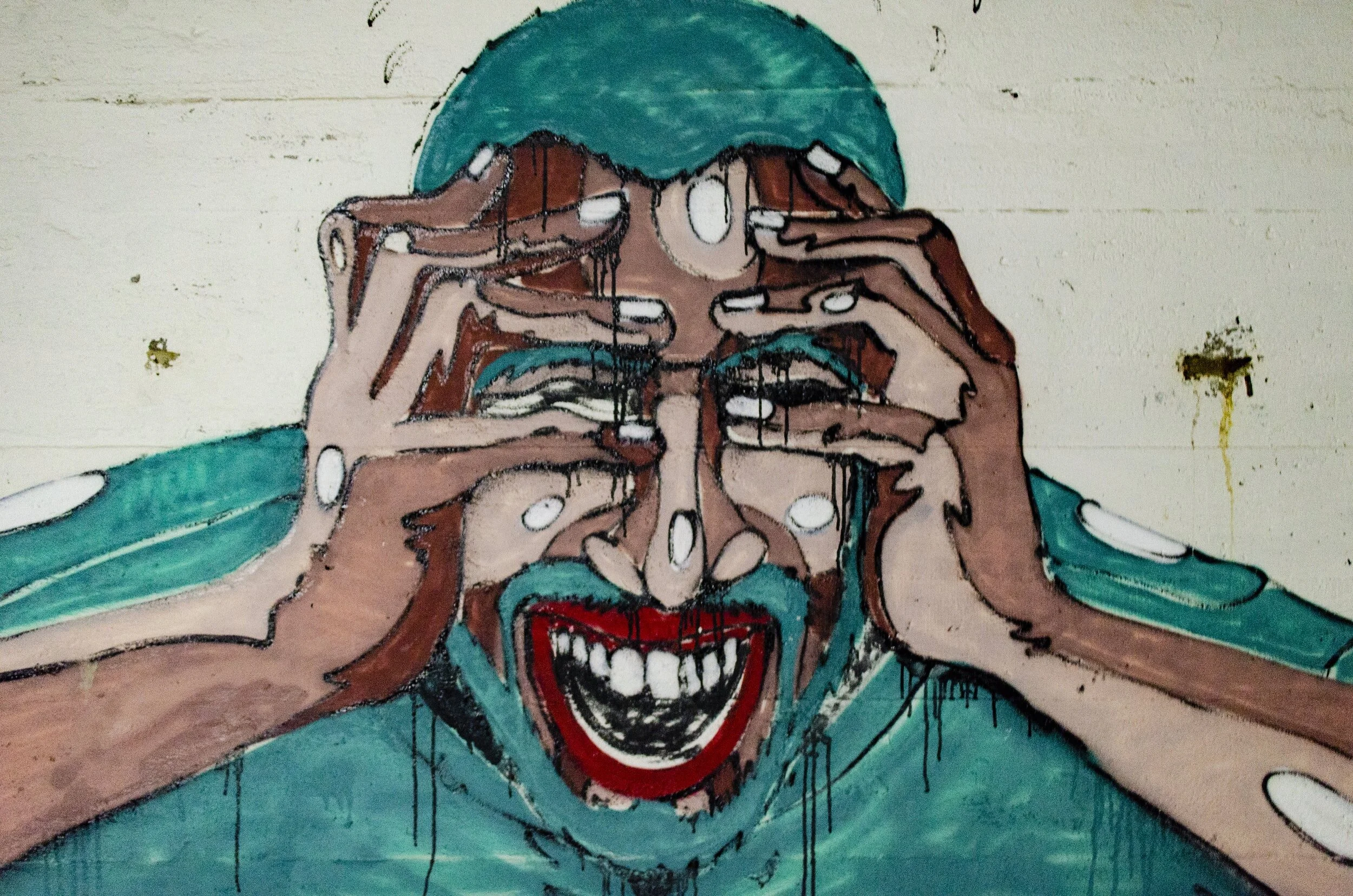 Graffiti artwork of a person in teal clothing, hands on face, smiling widely.