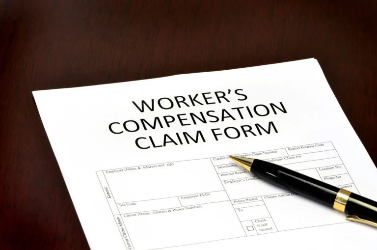 Worker's Compensation Claim Form on wooden desk with black and gold pen.