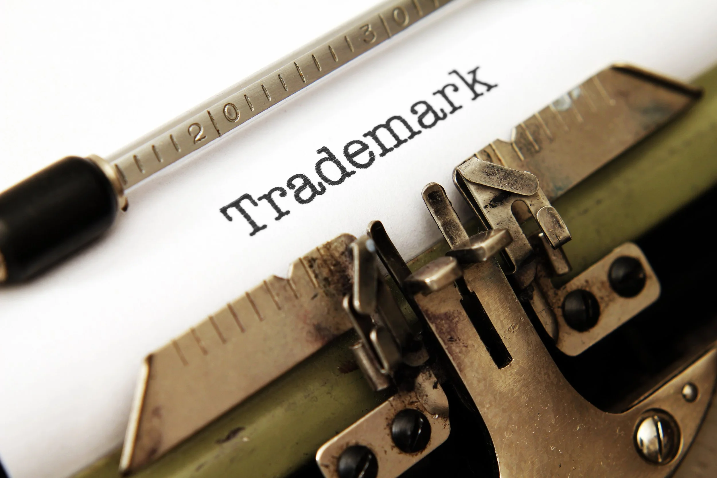 Close-up of vintage typewriter typing the word "Trademark" on white paper.
