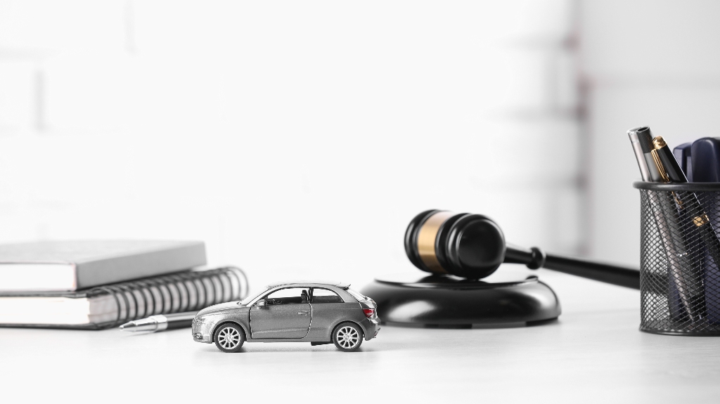 Toy car, judge's gavel and stationery on white table